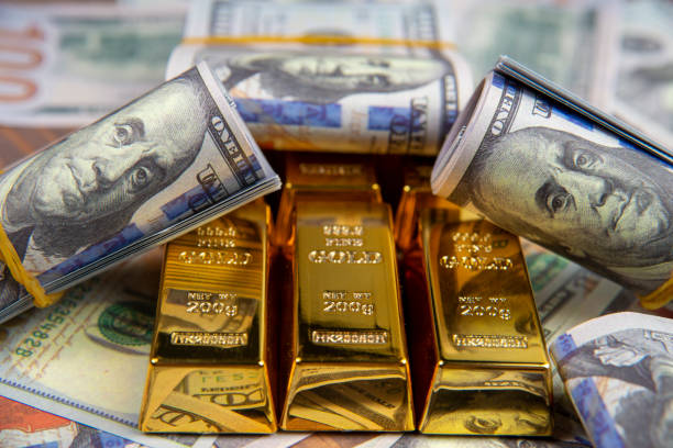 Gold bars and rolls of hundred-dollar bills, symbolizing the relationship between gold prices and the strengthening of the dollar in forex trading